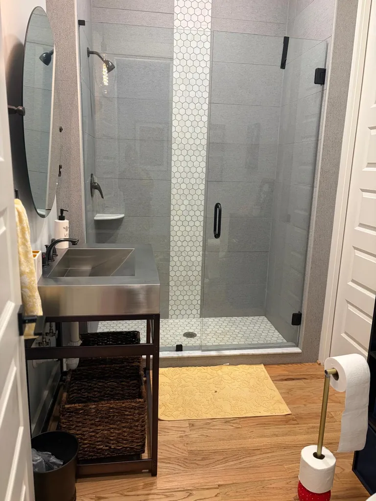 Glass shower with gray tile and a mosaic accent