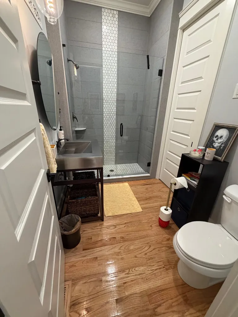 Bathroom with a glass shower and wood flooring
